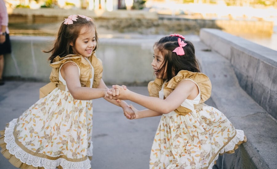 Young twin girls hold hands and dance, excited by their family's purchase of another home.