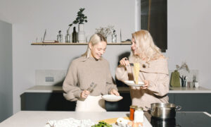 To show family co-ownership of a house, a mother and her adult daughter are cooking together in their kitchen