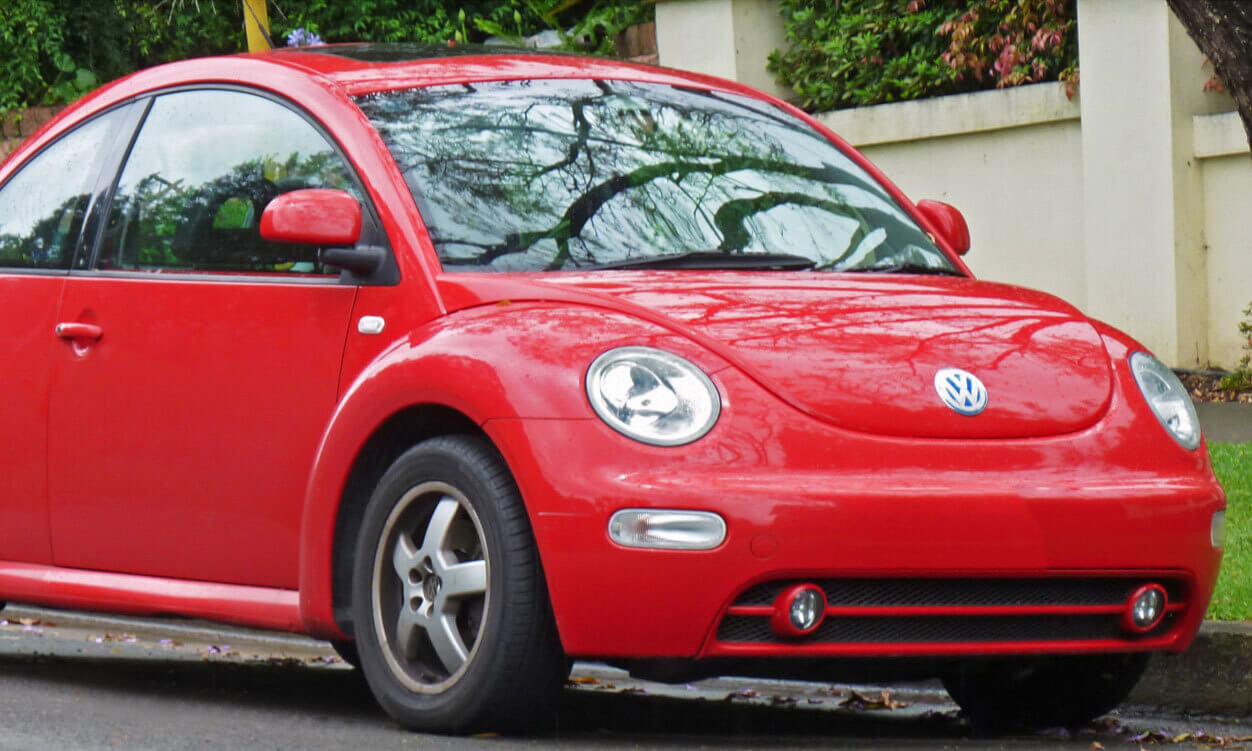 A red Volkswagen Beetle parked on a street