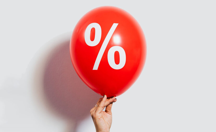 A woman is seen holding up a ballon with a percentage symbol in the background to symbolize the Bank of Canada September rate hike.