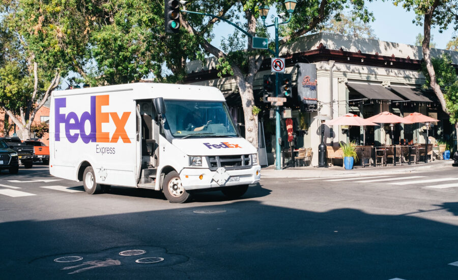 A FedEx truck sits at a curb at a busy street corner, to play on the words "FedEx delivers bad news."