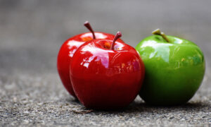 Two shiny red apples and a green apple are shown to symbolize the comparison of GICs and annuities for retirement