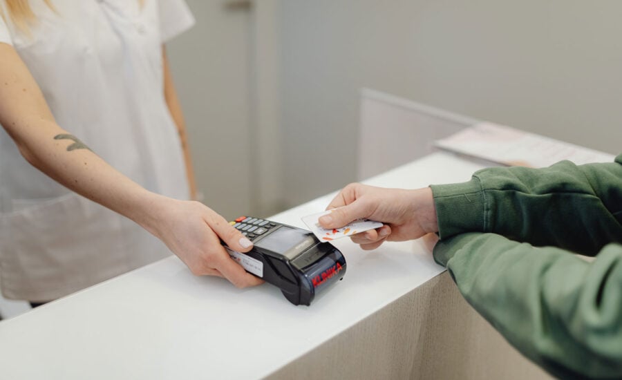 A man is tapping his credit card to pay for something, to symbolize how accustom to debt Canadians have become.