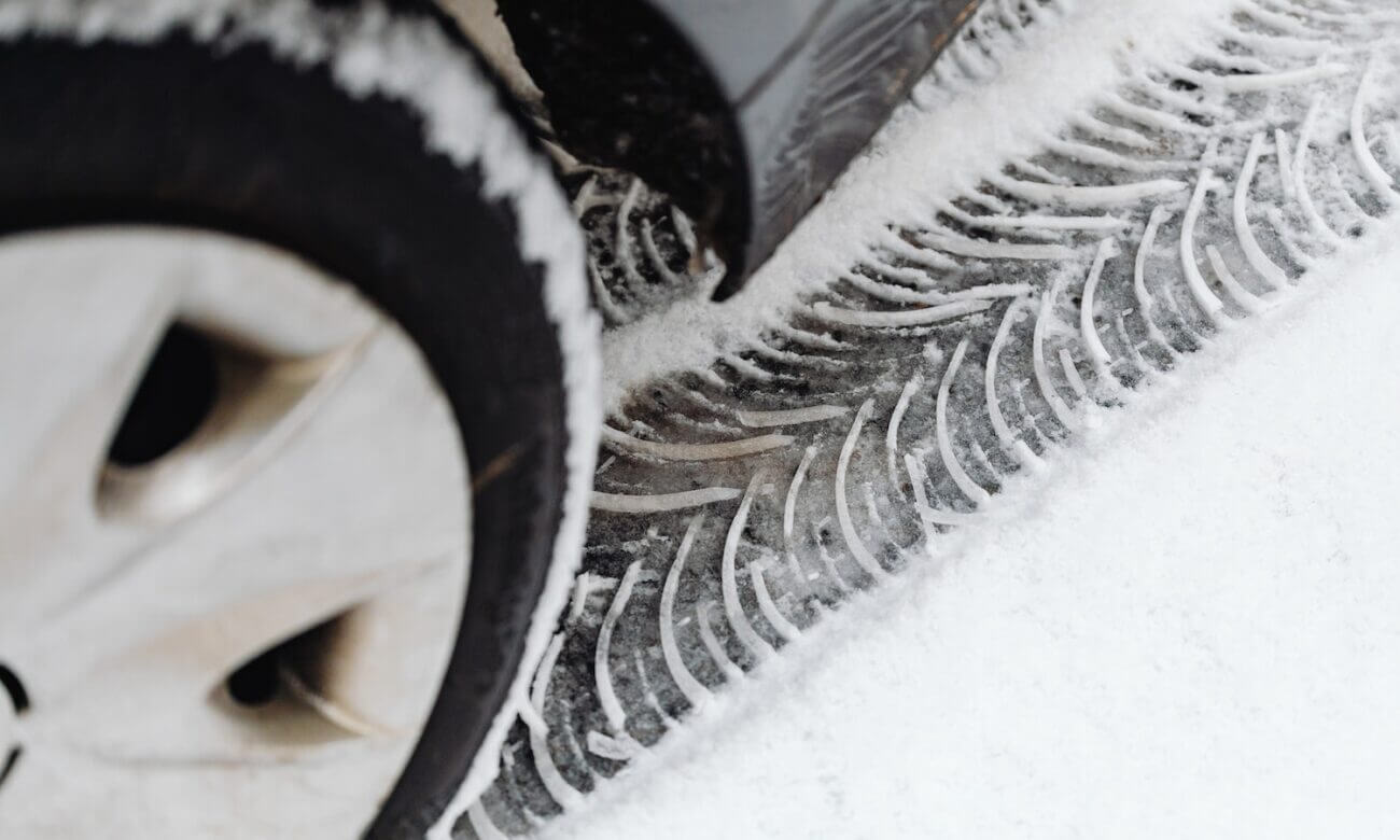 Close-up of a V-shaped tire track in the snow under a car