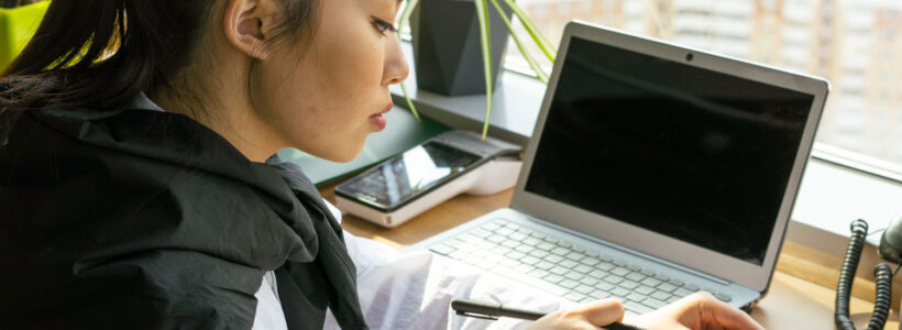 A woman is sitting at her desk, using her calculator to figure out her debt-to-income ratio.