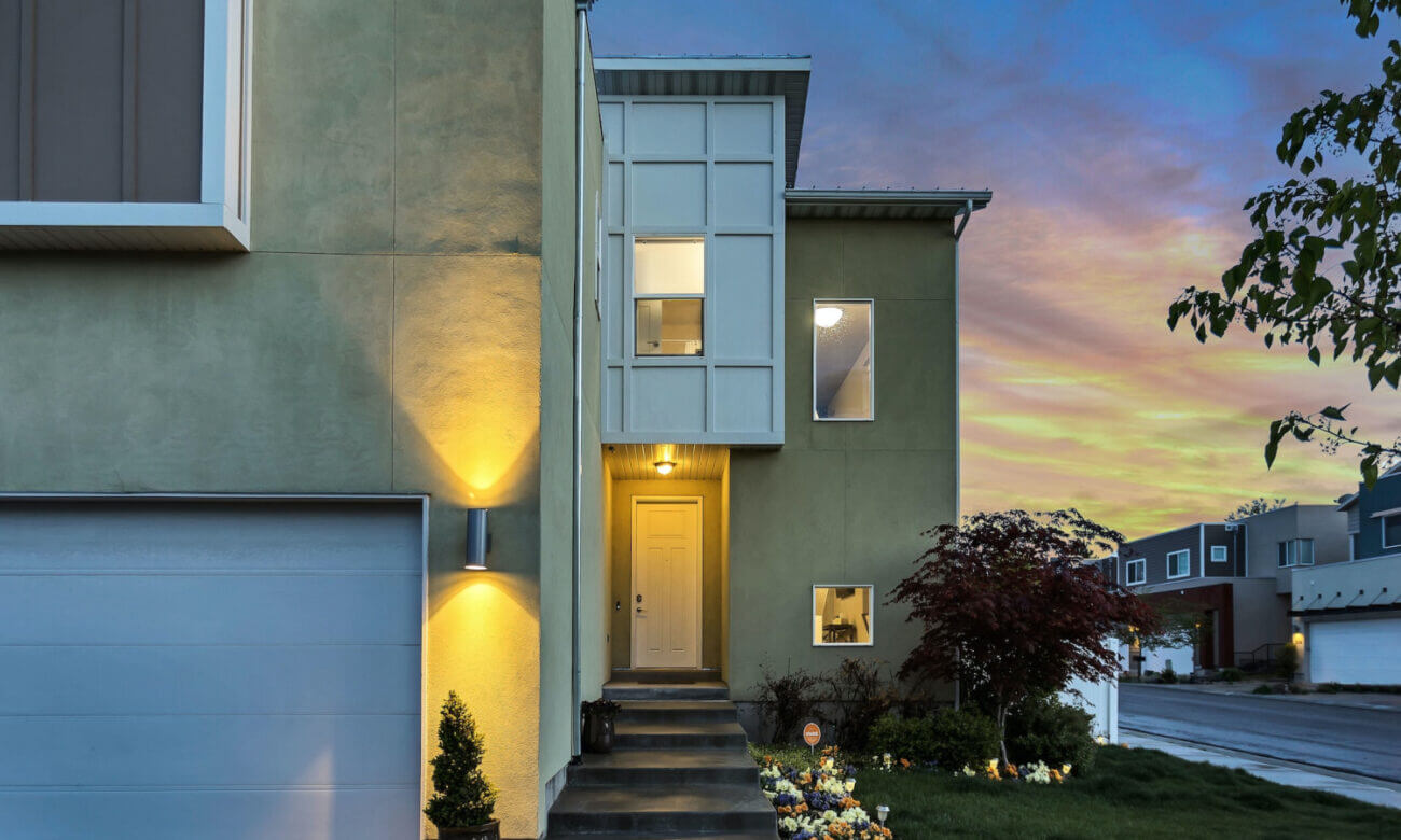 Lights glow in front a modern two-storey home at dusk