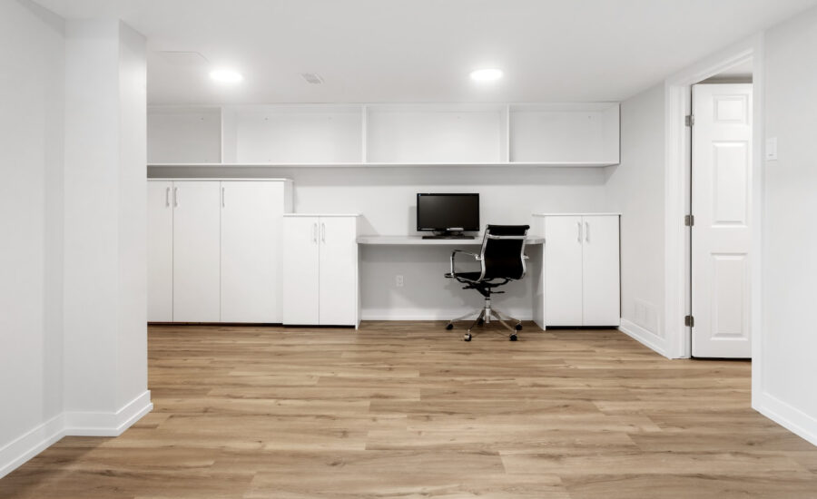 A newly renovated basement that remains empty, except for an office chair and computer monitor