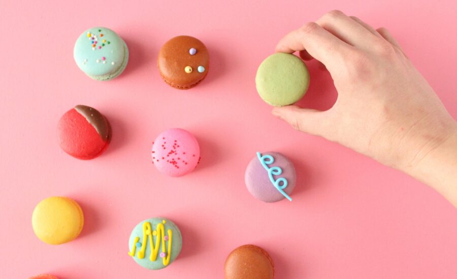 A hand picking up a macaron from a colourful assortment