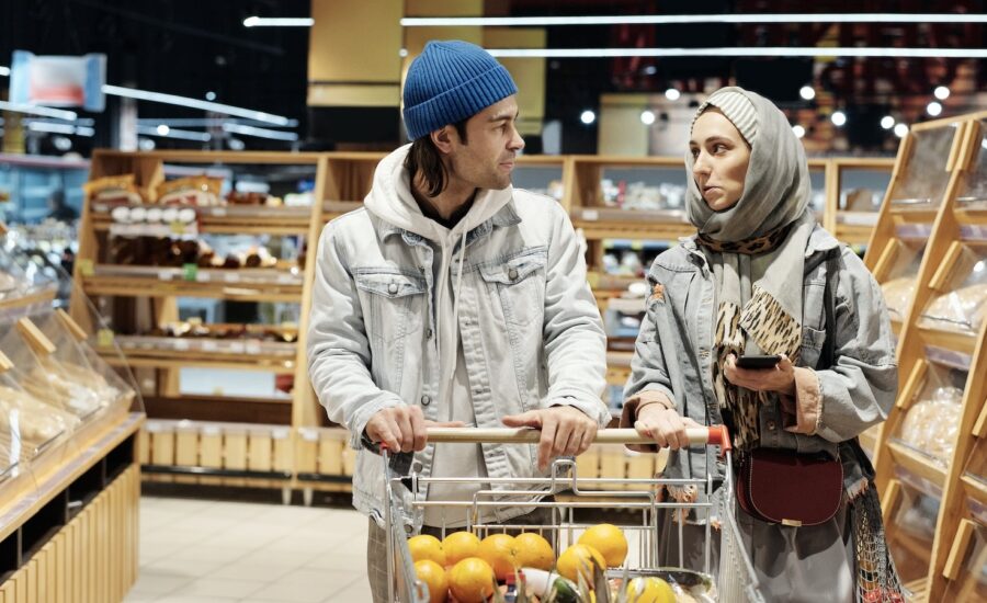 A young couple looking worried about inflation while grocery shopping
