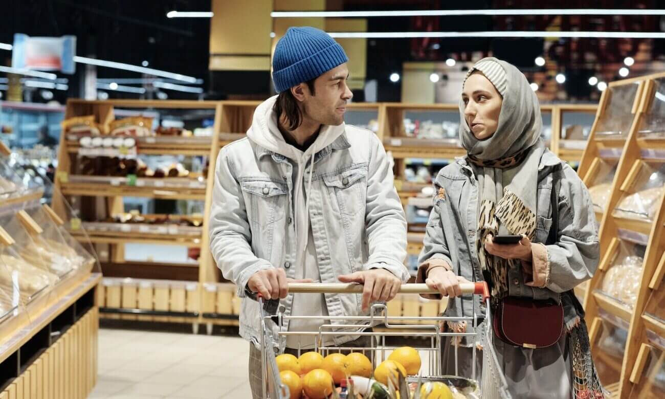 A young couple looking worried about inflation while grocery shopping