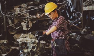 A woman in a hard hat works with machinery