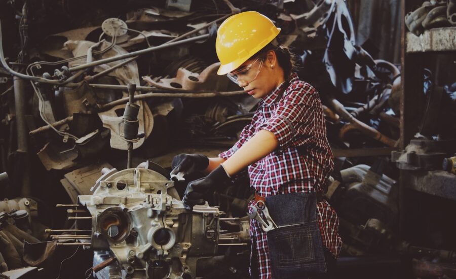 A woman in a hard hat works with machinery