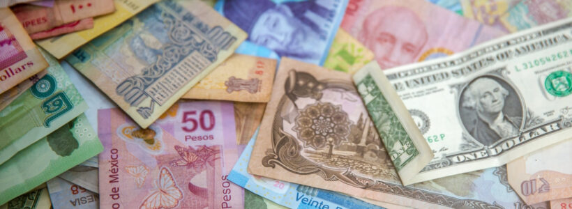 A pile of paper bills representing different currencies from around the world