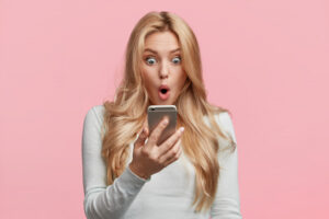A woman looks shocked while checking her credit score on her phone