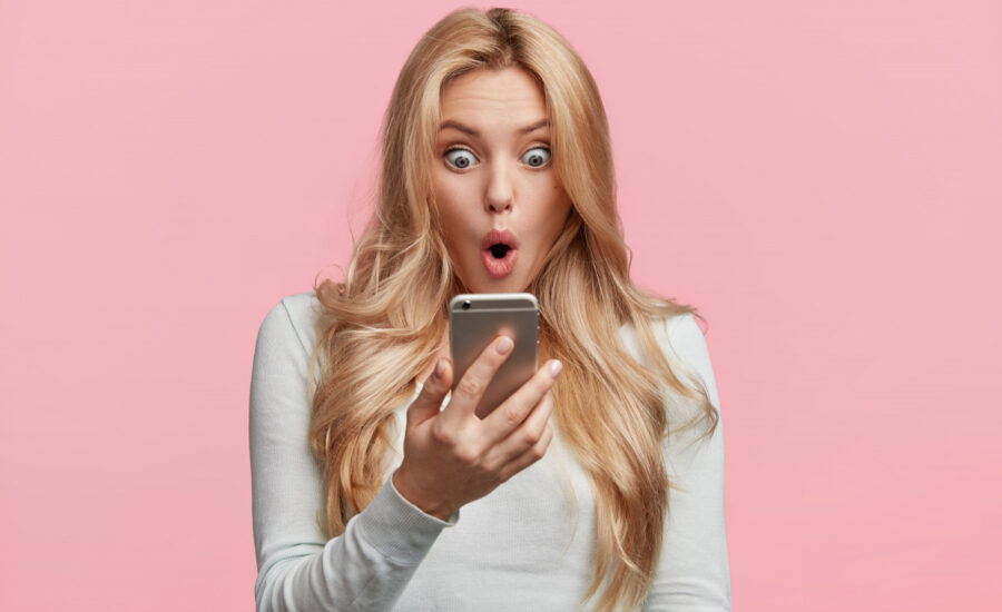 A woman looks shocked while checking her credit score on her phone