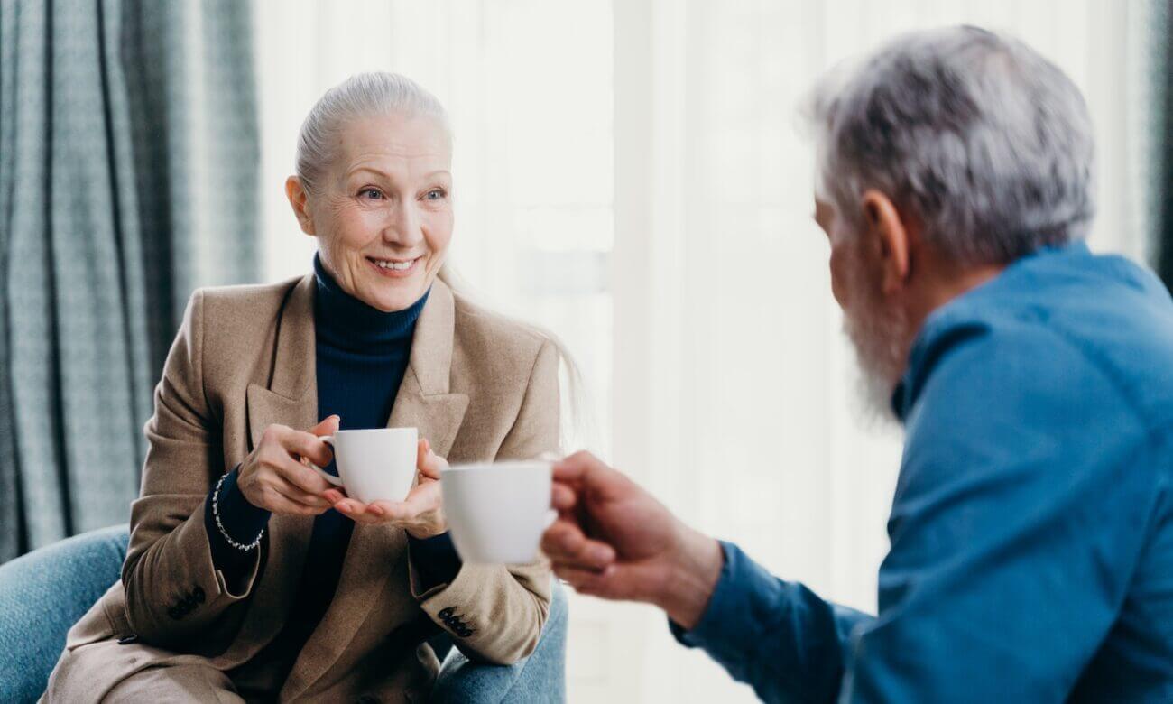 An elderly couple sits and shares a cup of coffee.