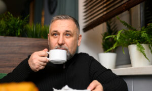 A middle-aged man drinks coffee in a cafe