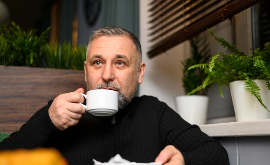 A middle-aged man drinks coffee in a cafe