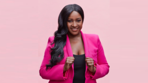 Founder Nathalie Smith smiles at the camera while wearing a bright pink blazer against a pink backdrop.