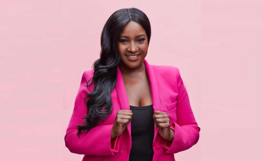 Founder Nathalie Smith smiles at the camera while wearing a bright pink blazer against a pink backdrop.