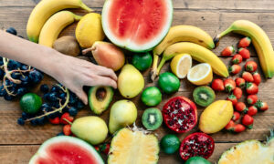 A hand chooses an avocado from an assortment of fresh produce