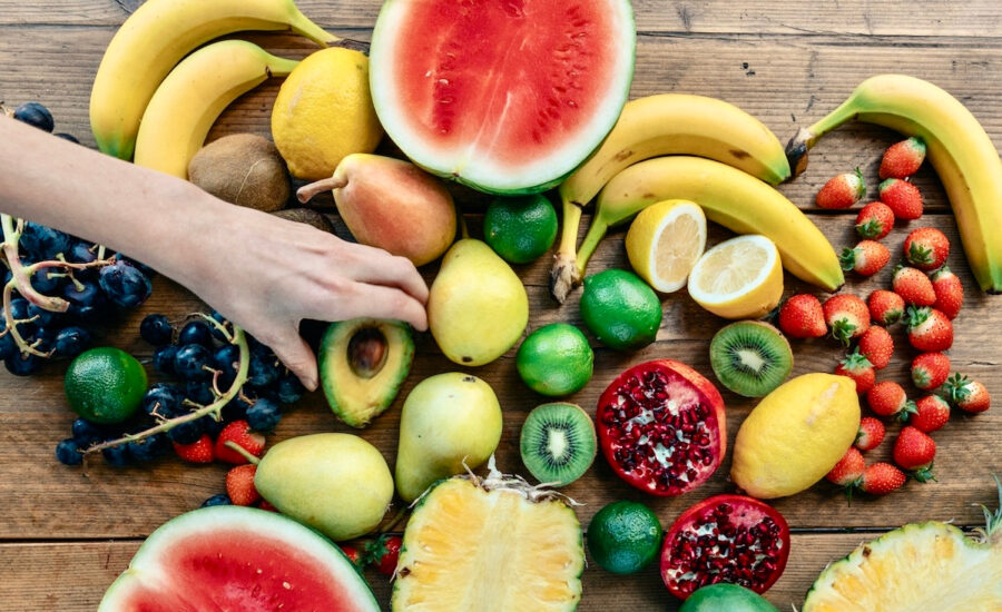 A hand chooses an avocado from an assortment of fresh produce