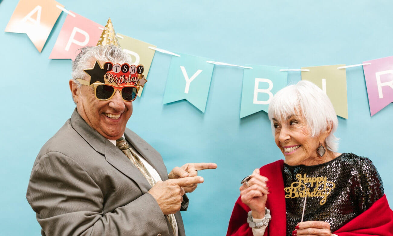 A senior-age couple in party clothes celebrate a birthday