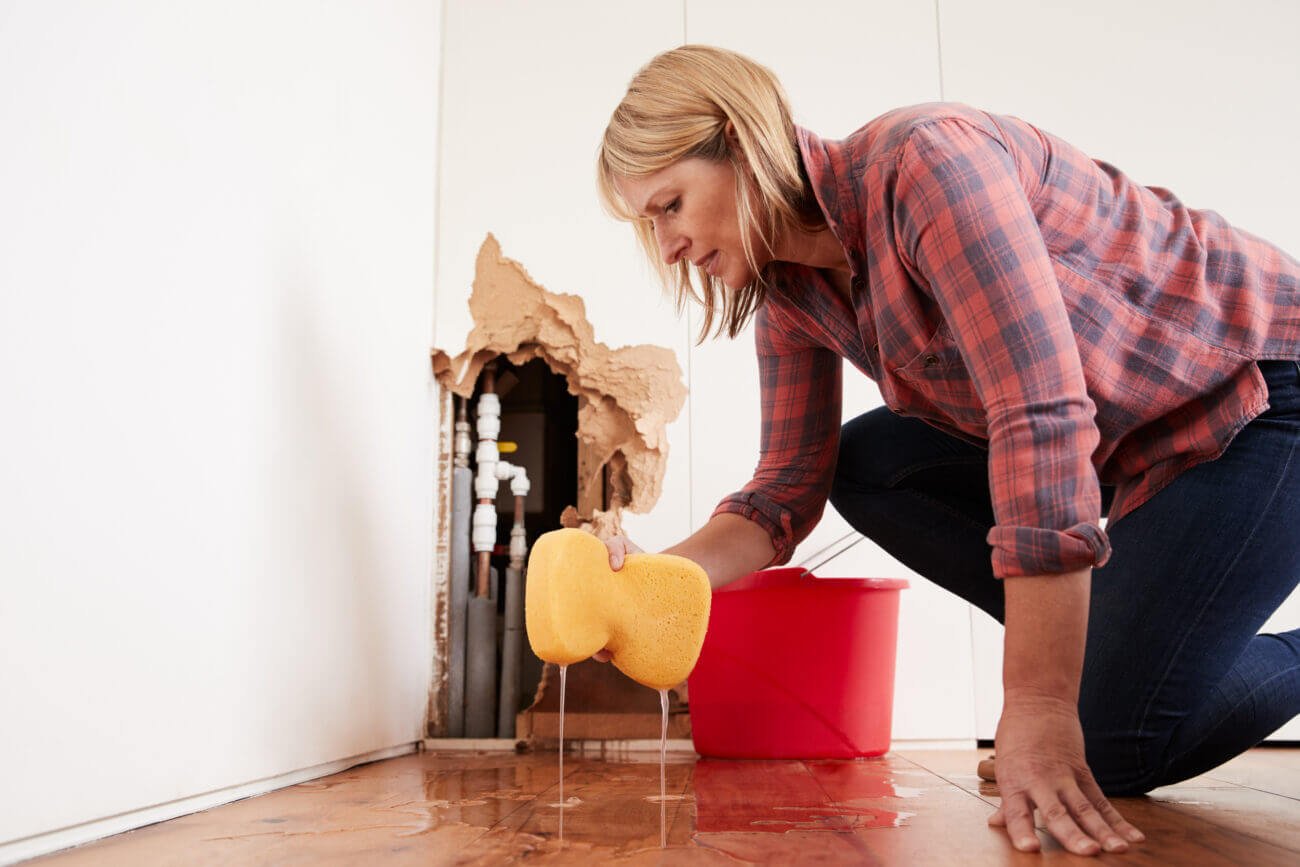A woman mops up a flooded floor with a large sponge