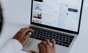 Hands are shown, typing on a laptop, to tie into the earnings reports below.