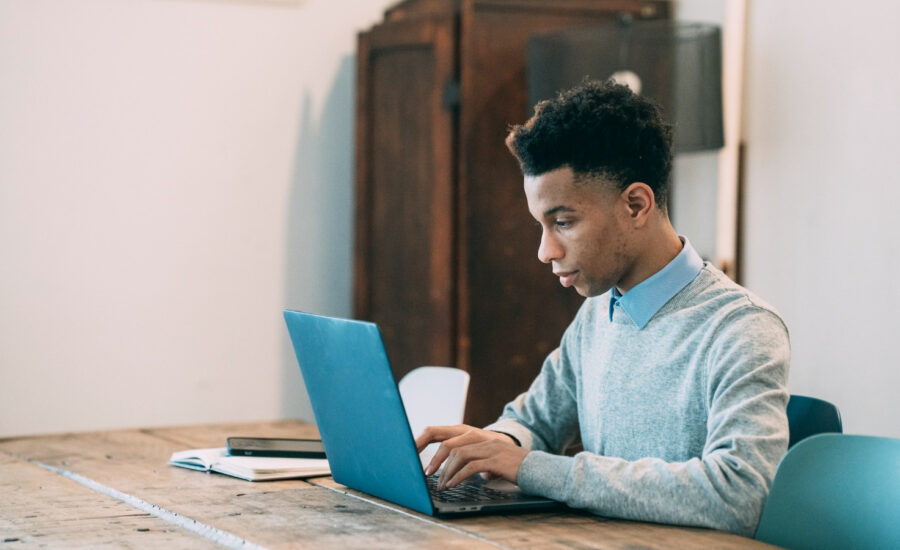 A young man enters the details of his budget on a laptop