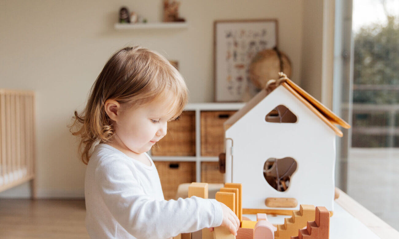 A toddler plays with a doll house to symbolize owning a home, after inheriting it from the grandparents.
