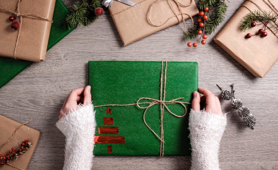 A pair of hands holds a gift wrapped in green paper