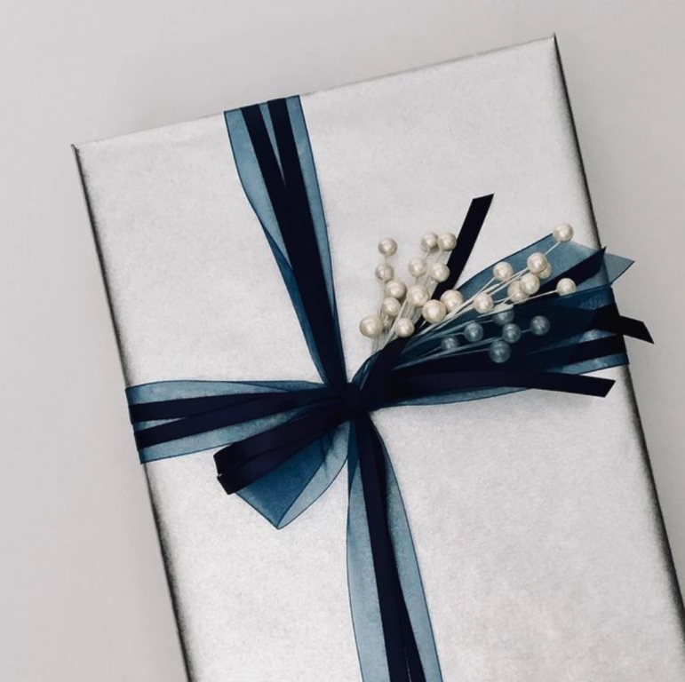 A box gift-wrapped in silver with a blue ribbon