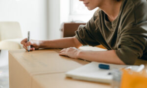 A woman writes on a box as she prepares to move into a co-owned property