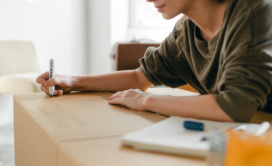 A woman writes on a box as she prepares to move into a co-owned property