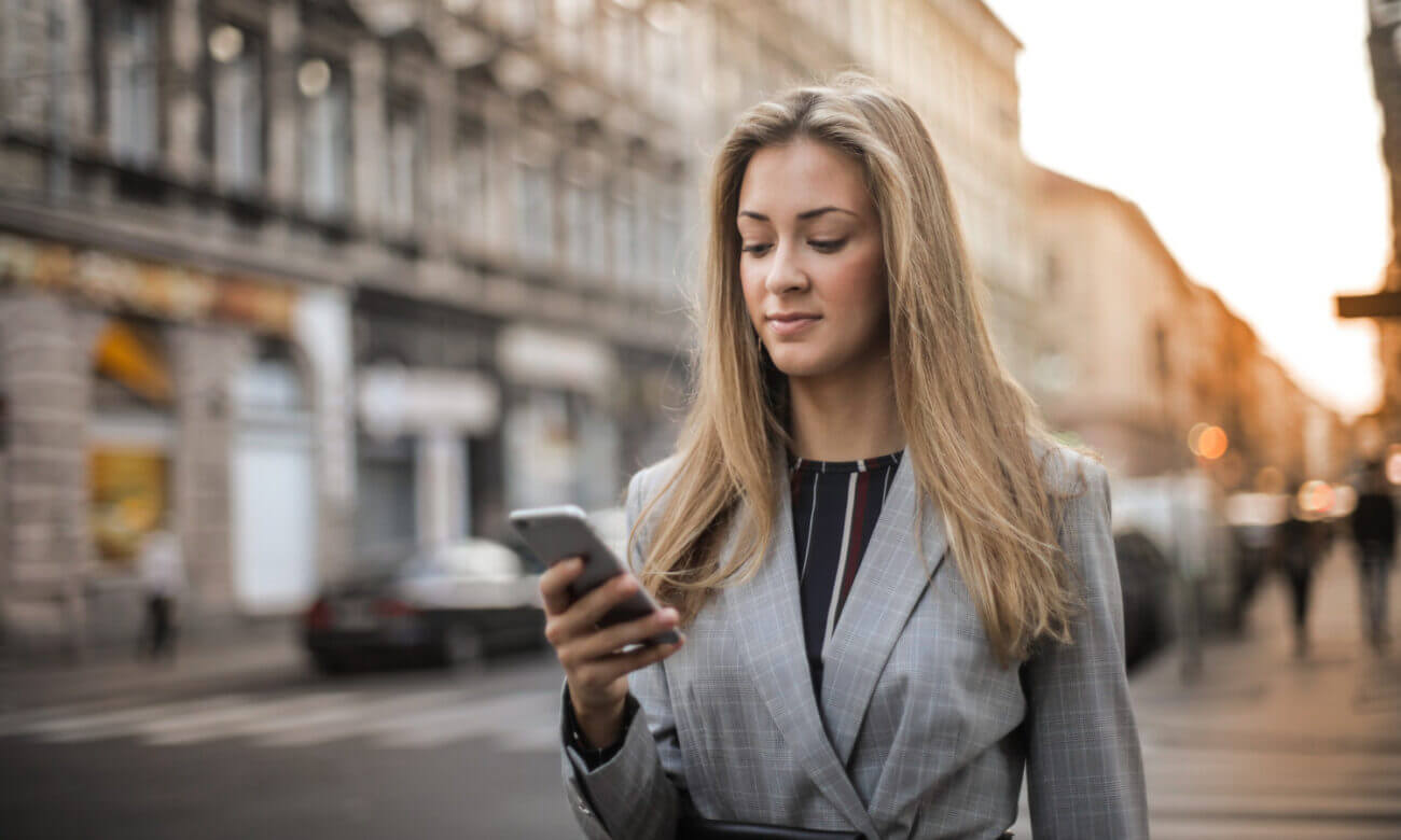 On the street, a well-dressed woman reviews for finances using an app on her phone