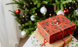 Three wrapped gifts in front of a Christmas tree