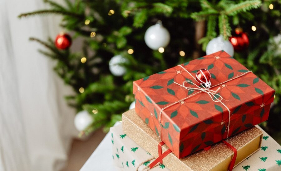 Three wrapped gifts in front of a Christmas tree