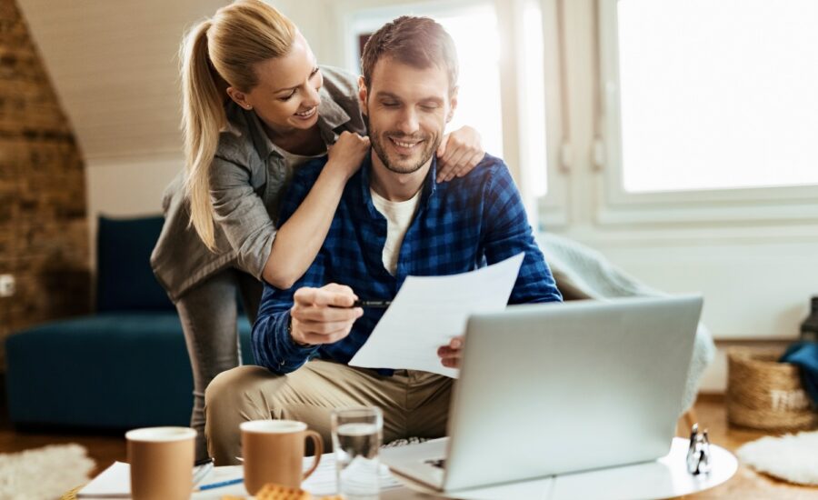 Couple in their 30s smile while reviewing a financial statement.