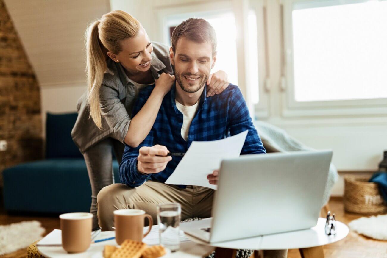 Couple in their 30s smile while reviewing a financial statement.