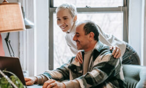 A cheerful couple review a list of RRSP accounts online using a laptop