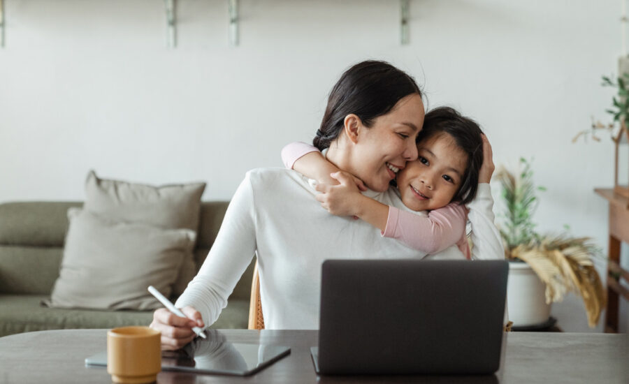 A woman hugs her daughter after reading about her RESP options online