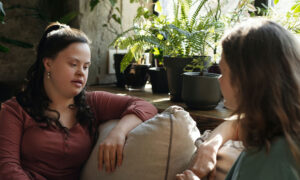 A mother and daughter are seated on a couch discussing plans for a disabled beneficiary trust