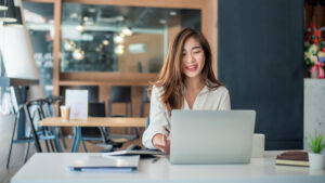 Young woman smiles at her laptop in an office