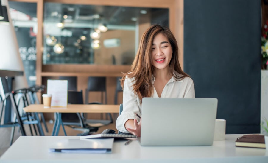 Young woman smiles at her laptop in an office