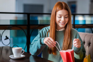 A smiling woman at a cafe looks into a shopping bag