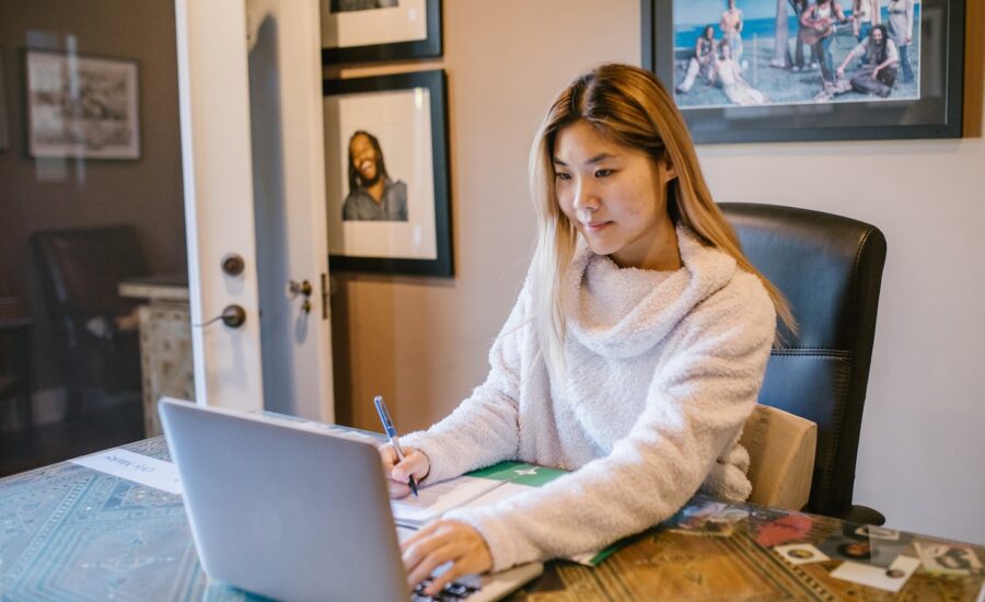 A woman checks her online banking on her laptop at her desk.