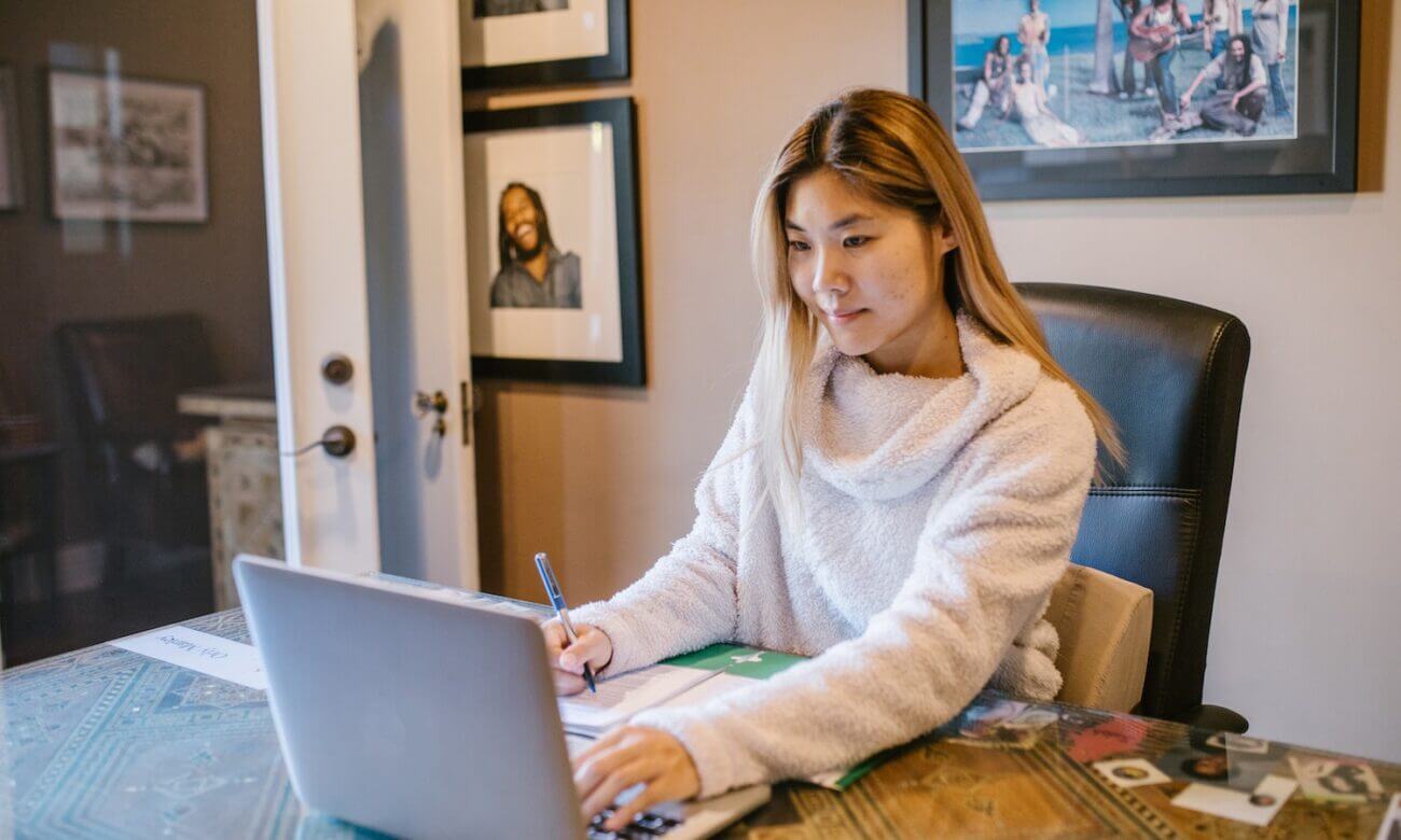 A woman checks her online banking on her laptop at her desk.