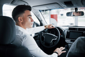 A young man in the driver's seat of a car listens to his instructor