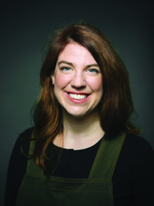 Author and financial planner Shannon Lee Simmons smiles for the camera against a dark background.